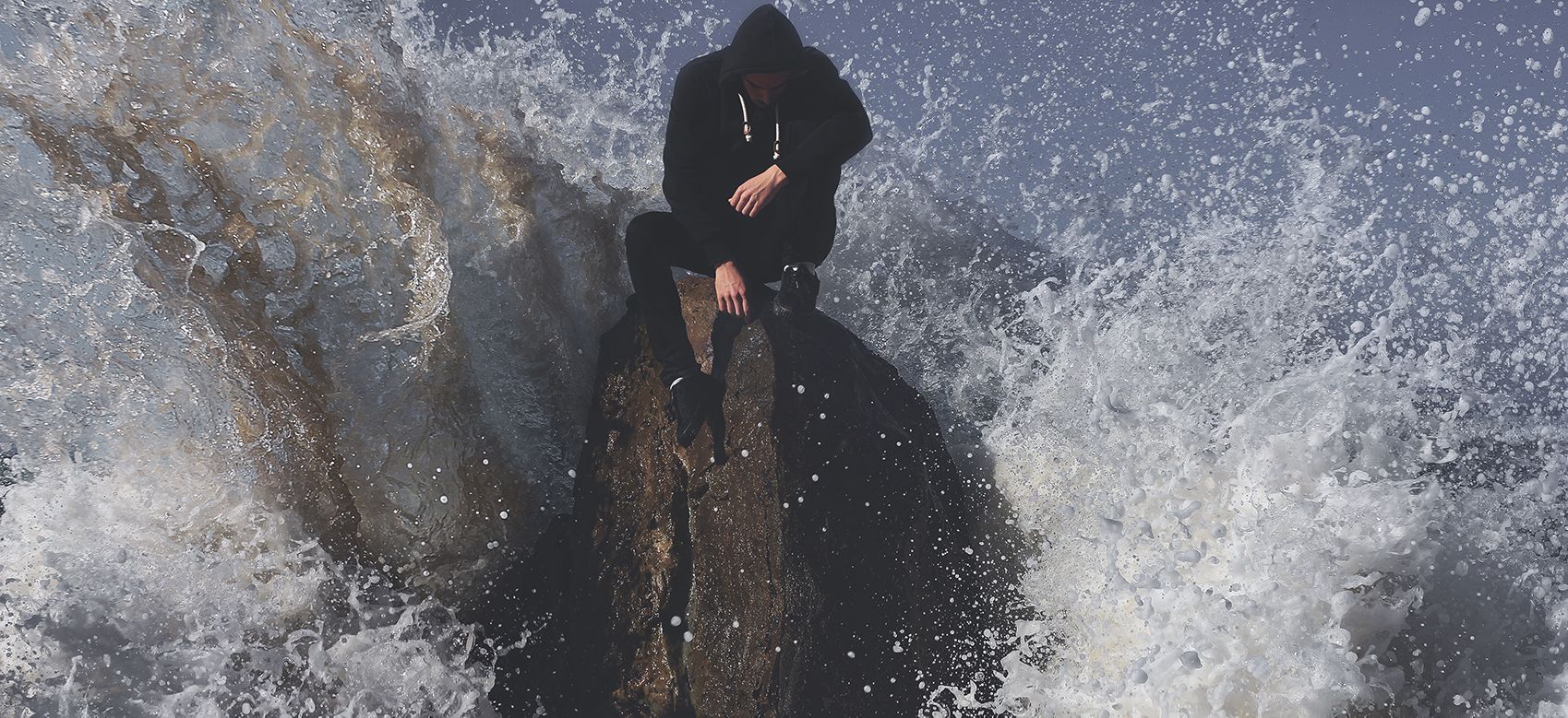 man on rock in waves